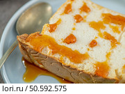 Close-up of a delicious slice of molotof, a traditional caramelized egg white pudding, generously drizzled with sweet syrup on a light blue plate with a silver spoon. Стоковое фото, агентство Ingram Publishing / Фотобанк Лори