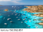Aerial view of luxury yachts and boats moored in the crystal-clear turquoise waters of a beautiful sea bay in sardinia, italy, creating a picturesque scene of summer vacation and leisure. Top view. Capturing sardinia’s stunning coastline from above, yachts and sailboats dotting the crystal-clear turquoise waters evoke a scene of luxurious leisure and maritime beauty. Стоковое фото, агентство Ingram Publishing / Фотобанк Лори
