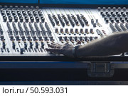 Technician's left hand makes adjustment on audio control panel in booth at outdoor concert. Стоковое фото, агентство Ingram Publishing / Фотобанк Лори