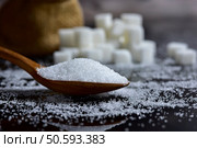Closeup sugar piling up the shape of the hill from wooden spoons and sugar cubes on a black background. selective focus. Стоковое фото, агентство Ingram Publishing / Фотобанк Лори