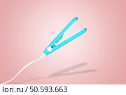 levitating hair curling iron over pink background. Стоковое фото, агентство Ingram Publishing / Фотобанк Лори