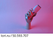 Wooden hand holding hair clipper in pink blue gradient neon light. Стоковое фото, агентство Ingram Publishing / Фотобанк Лори