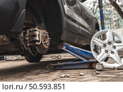 The car was raised  to change tires using a hydraulic jack placed under the car.Wheel is being replaced. Стоковое фото, фотограф Михаил Яковлев / Фотобанк Лори