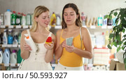 Cheerful young besties in light summer clothes examining bottles of sunscreen and tanning lotion in store, discussing choice of product ensuring skincare and UV protection while preparing for vacation. Стоковое видео, видеограф Яков Филимонов / Фотобанк Лори