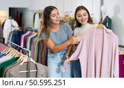 Happy young women testing fabrics of pink cardigan while shopping in a mall. Стоковое фото, фотограф Яков Филимонов / Фотобанк Лори