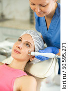 Adult woman cosmetologist doing microcurrent procedure to young woman. Стоковое фото, фотограф Яков Филимонов / Фотобанк Лори