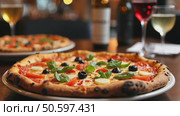 Authentic gourmet pizza selection served on restaurant table for sharing between friends during night out. Fresh ingredients and crispy crust on Italian traditional cuisine. Стоковое AI-видео, аниматор Sergey Grishin / Фотобанк Лори
