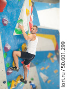 Atlete man grabbing ledges of artificial climbing wall in bouldering centre. Стоковое фото, фотограф Яков Филимонов / Фотобанк Лори