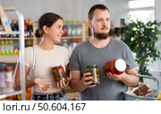 Spouses make choice choose consider canned vegetables in store. Стоковое фото, фотограф Яков Филимонов / Фотобанк Лори