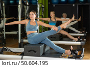 Woman in sports top and leggings doing exercises on reformer. Стоковое фото, фотограф Яков Филимонов / Фотобанк Лори