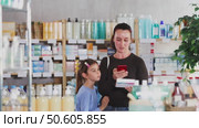 Woman with a child scans the barcode of a package of pills for children. Buyer pays for goods in the pharmacy using the online application. Стоковое видео, видеограф Яков Филимонов / Фотобанк Лори