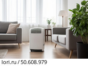 Portable dehumidifier purifying air in living room with modern interior. Стоковое AI-изображение, AI-художник Иван Рябоконь / Фотобанк Лори