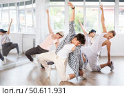 Man and his students perform hip hop dance on one bent leg, movement in horizontal plane near floor. Стоковое фото, фотограф Яков Филимонов / Фотобанк Лори