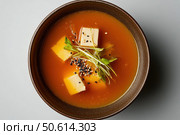 This aerial view of miso soup highlights its symmetry and restraint. The Japanese dish, beautifully arranged, showcases tofu, seaweed, and green onions submerged in a rich, umami broth. Стоковое AI-изображение, AI-художник Nart / Фотобанк Лори