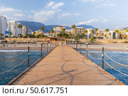 Wooden pier extending to a beautiful coastal cityscape with palm trees (2024 год). Редакционное фото, фотограф EugeneSergeev / Фотобанк Лори