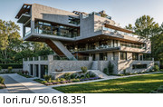 Modern architectural house with large windows and unique design. Стоковое AI-изображение, AI-художник Андрей Бажанов / Фотобанк Лори