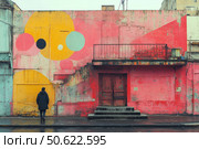 An urban scene with colorful graffiti painting on the facade of an old building. On top of peeling pink and yellow plaster, geometric figures in the style of street art are painted - circles and abstract shapes. In front of the building stands a man in dark clothes, looking at the wall, creating a sense of reflection and loneliness. The scene is captured on a cloudy day, the asphalt is shining from the rain. This photo is perfect for urban themes, street art, urban contrasts and visual stories. Стоковое AI-изображение, AI-художник Анна Кривицкая / Фотобанк Лори