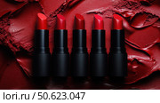 Row of passion red lipsticks displayed against a vibrant red textured background. Beauty industry and fashion concept. Copy space. Advertisement for makeup artists. Стоковое AI-изображение, AI-художник Ирина Михайличенко / Фотобанк Лори