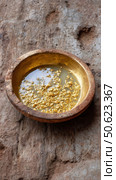 Gold panning showing gold dust and nuggets concentrated in a pan. Стоковое AI-изображение, AI-художник Юрий Поздников / Фотобанк Лори