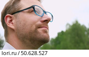 Confident Businessman in Natural Setting. Man stands in front of lush green backdrop. Remote working. Portrait of happy mid adult male wearing formal clothes, shirt and tie, glasses. Find inspiration. Стоковое видео, видеограф Марина Демидюк / Фотобанк Лори