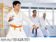 Young judo fighter in kimono practicing punches durig kata with group. Стоковое фото, фотограф Яков Филимонов / Фотобанк Лори