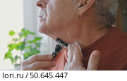 Senior Man shaving his face. Old male shaves beard and mustache with shaver. Elderly gray haired man looking at the mirror, applies shaving cream foam and using razor. Skin hygiene. Daily body care. Стоковое видео, видеограф Марина Демидюк / Фотобанк Лори
