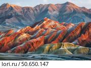 Zhangye danxia landform geological park showcasing colorful red, orange, and rainbow mountains at sunset. Стоковое AI-изображение, AI-художник Иван Рябоконь / Фотобанк Лори
