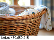 Wicker laundry basket overflowing with freshly washed clothes. Стоковое AI-изображение, AI-художник Иван Рябоконь / Фотобанк Лори