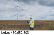 A safety expert inspects the wind turbine for any potential risks on a wet day before a thunderstorm. Стоковое видео, видеограф Strunov David / Фотобанк Лори