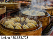 Steaming baskets of delicious dumplings releasing flavorful steam. Стоковое AI-изображение, AI-художник Иван Рябоконь / Фотобанк Лори