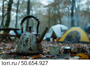 Rustic camping scene with weathered kettle and tents. Стоковое AI-изображение, AI-художник Иван Рябоконь / Фотобанк Лори