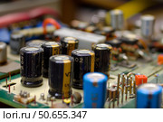 Electrolytic capacitors populating surface of printed circuit board. Стоковое AI-изображение, AI-художник Иван Рябоконь / Фотобанк Лори