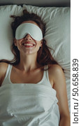 Happy millennial woman lying in bed with sleeping mask. Стоковое AI-видео, аниматор Sergey Grishin / Фотобанк Лори