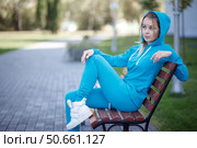Smiling girl in blue tracksuit sitting on wooden bench outdoors looking at camera. Стоковое фото, фотограф Роготнева Виктория / Фотобанк Лори