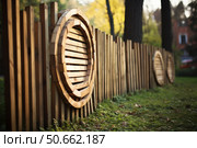 Modern round wood fence enclosing green grass area in a park. Стоковое AI-изображение, AI-художник Иван Рябоконь / Фотобанк Лори