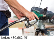 Gas station. A gas station attendant in a car's fuel tank. A man refuels a car with gasoline. Rising fuel prices worldwide. Стоковое фото, фотограф Photojuli / Фотобанк Лори