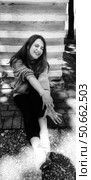Красивая женщина 38 лет с длинными темными волосами в светлой толстовке сидит у ребристой стены и потягивается. Стоковое фото, фотограф Светлана Русских / Фотобанк Лори