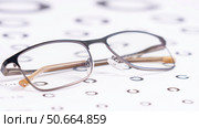 Eyeglasses On White Table Symbols For Close-Up Visual Acuity Test. Concept of wearing optical glasses for human vision correction. Deterioration of vision with age. Vision test method. Стоковое фото, фотограф Скрипачев Антон / Фотобанк Лори