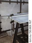 Fixing a square metal pipe with a metal clamp and a sheet of straight slate on a workbench at a construction site. Стоковое фото, фотограф Неведицына Елена / Фотобанк Лори