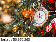 Golden retro clock on a Christmas tree. The clock hands show 12 o'clock. Beautiful background for New Year's Eve or Christmas 2026. Стоковое фото, фотограф Photojuli / Фотобанк Лори