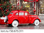 A vintage red Christmas car is carrying a Christmas tree on its roof. Decorated New Year's Moscow. Product delivery concept. Стоковое фото, фотограф Photojuli / Фотобанк Лори