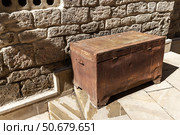 Old rustic wooden chest placed against a textured stone wall. Стоковое фото, фотограф EugeneSergeev / Фотобанк Лори