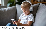 Cute kid boy lwatching smartphone. Children's screen time. Child plays games using phone at the evening or night. Social media addiction. Childhood, modern technology. Стоковое AI-изображение, AI-художник Ирина Гильмуллина / Фотобанк Лори