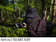 Фотограф снимает растения на фотоаппарат. Девушка фотограф в черной панаме держит фотоаппарат в руках. Синхронизатор и вспышка в руках фотографа. (2024 год). Редакционное фото, фотограф Валентина Игнатенко / Фотобанк Лори