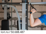 Gym. The picture shows a young man exercising his arms using a pull-up machine. Sports and a healthy lifestyle. Стоковое фото, фотограф Photojuli / Фотобанк Лори