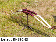 Two wooden traditional handmade bows stand on a holder on a green meadow during the Erdynskie Games, an archery competition among men of the nomadic peoples of Eurasia on Baikal Lake coast. Стоковое фото, фотограф Виктория Катьянова / Фотобанк Лори