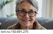 Smiling middle aged mature grey haired woman looking at camera, happy old lady in glasses posing at home indoor, positive single senior retired female sitting on sofa in living room. Стоковое AI-видео, аниматор Sergey Grishin / Фотобанк Лори