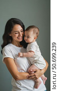 A Joyful Mother Embraces Her Baby, Both Sharing a Moment Filled With Love Against a Soft Grey Background. Стоковое AI-видео, аниматор Sergey Grishin / Фотобанк Лори