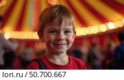 European Caucasian blonde boy child experiencing circus magic with colorful dome tent background marking World Circus Day. Inclusive entertainment joy. Стоковое AI-изображение, AI-художник Светлана Леуто / Фотобанк Лори