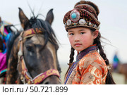 Young mongolian girl wearing traditional hat and clothing posing near her horse. Стоковое AI-изображение, AI-художник Иван Рябоконь / Фотобанк Лори